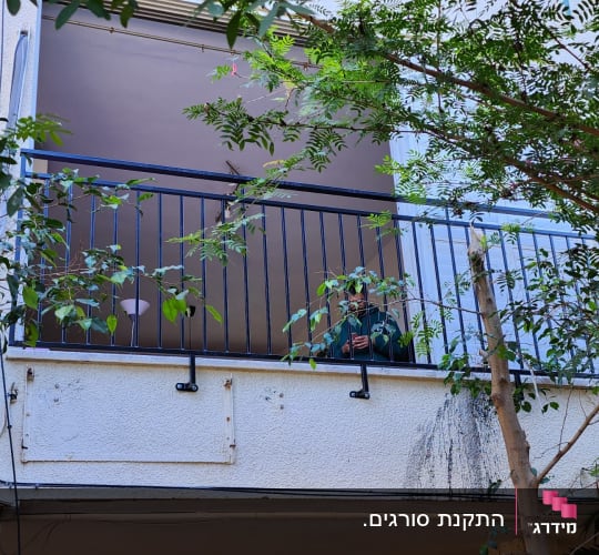 מעקה מתכת שחור במרפסת עם צמחייה מסביב